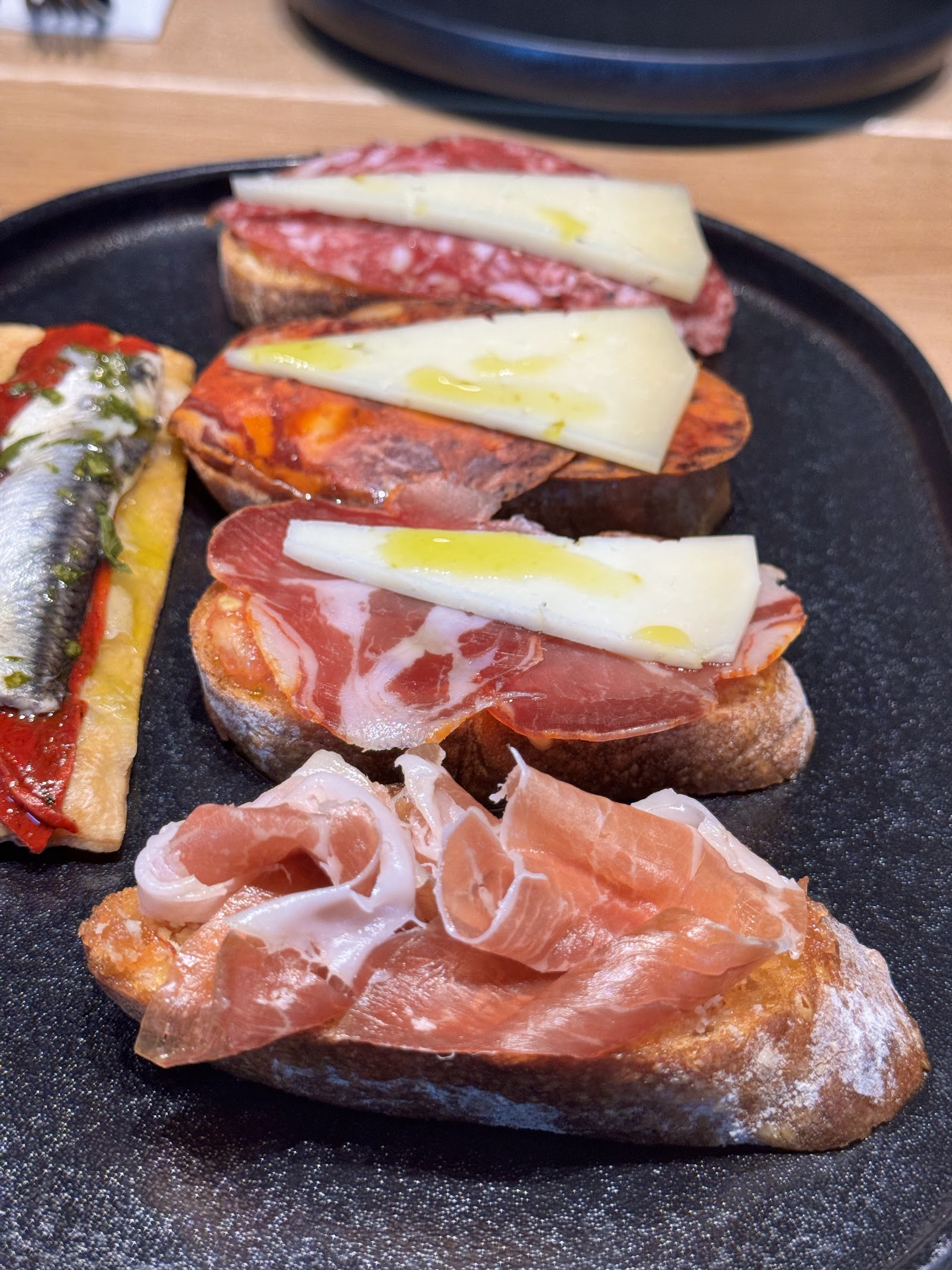 Rozmanité tapas: jamón, sýr a ančovičky na pečivu.
