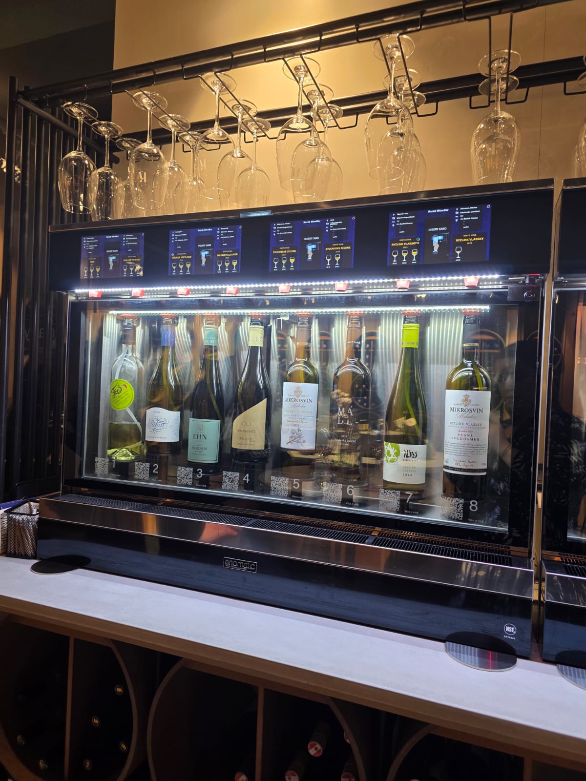 Moderní vinný automat s osmi lahvemi vína.
